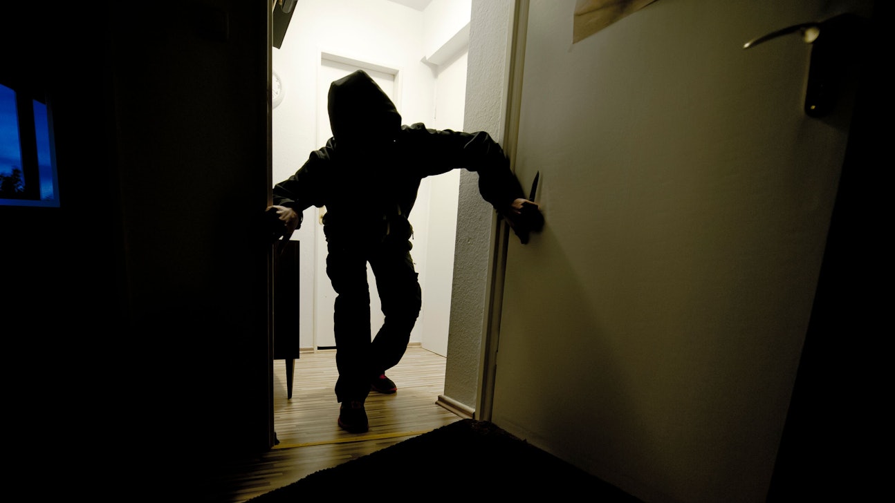 Ein mit einem Messer bewaffneter Mann schleicht durch eine Wohnung. Das Foto wurde gestellt.