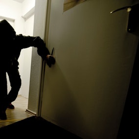 Ein mit einem Messer bewaffneter Mann schleicht durch eine Wohnung. Das Foto wurde gestellt.