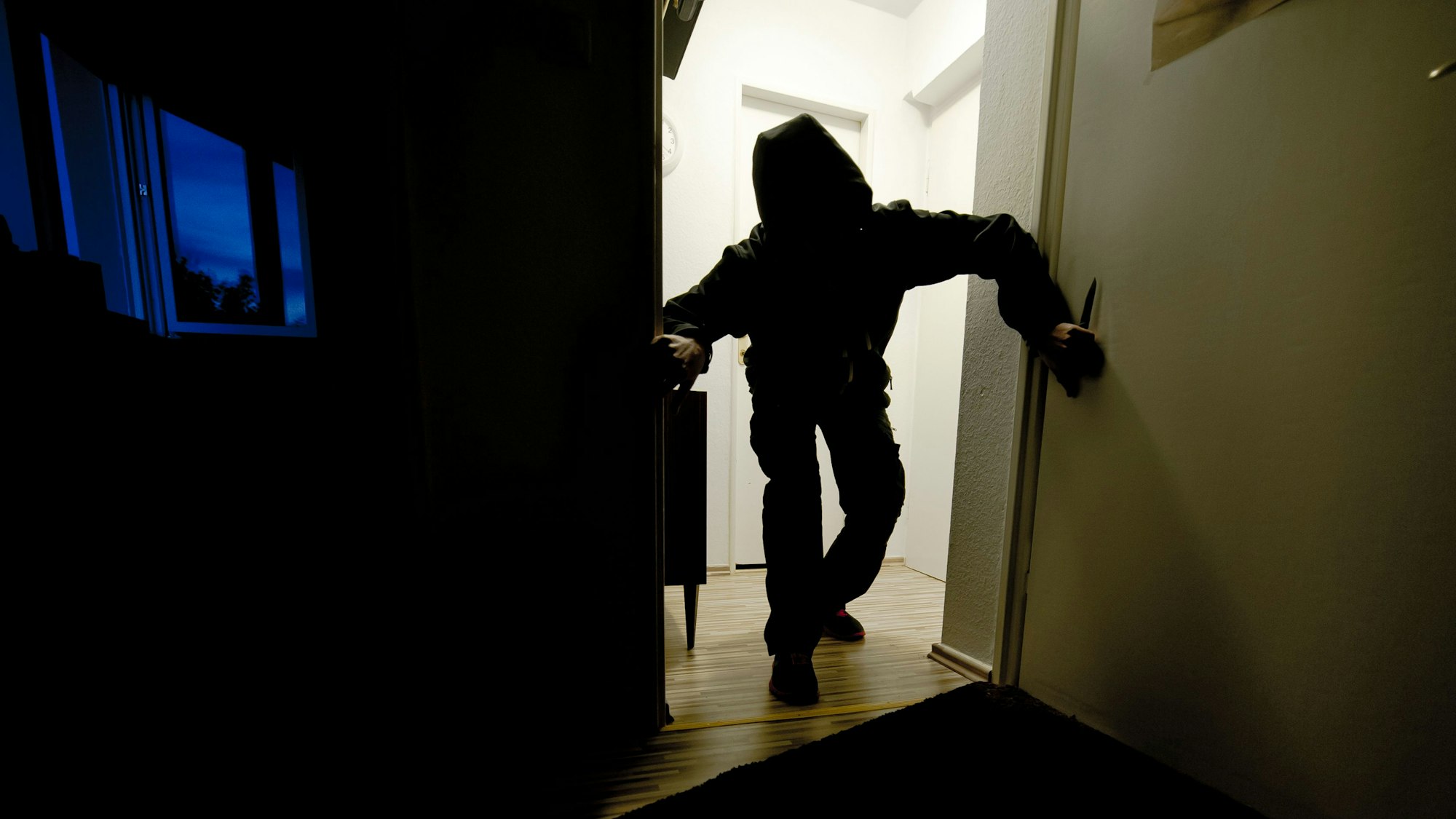 Ein Mann schleicht im Dunkeln durch eine Wohnung.