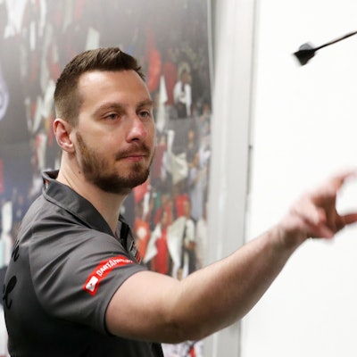 Darts-Profi Florian Hempel im Vip-Zelt des FC Viktoria Köln. Er hat gerade einen Dart-Pfeil geworfen. Der Pfeil fliegt vor ihm.