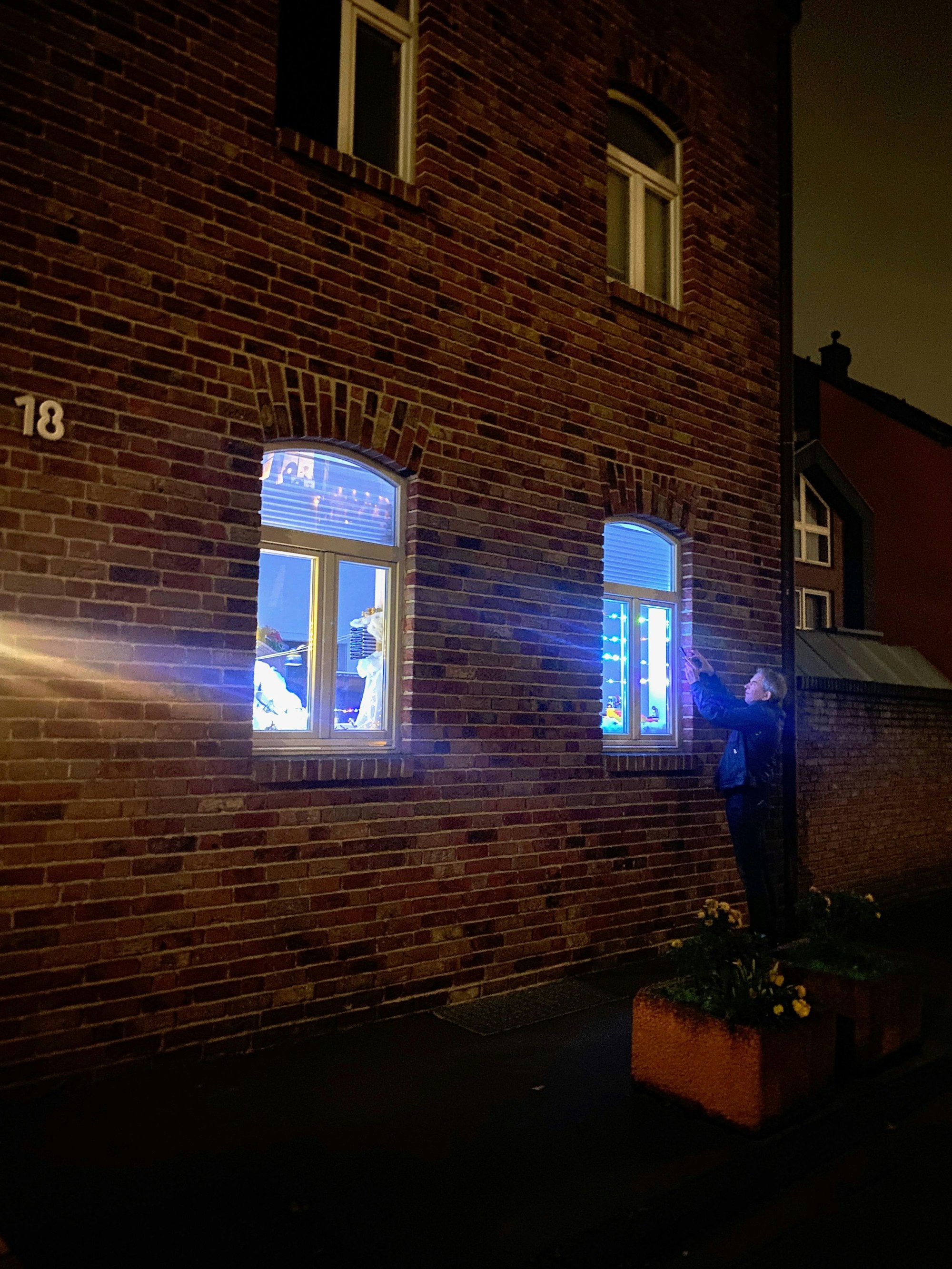 Ein Mann fotografiert von außen eins der erleuchteten und als Lego-Landschaft dekorierten Fenster an einer nächtlichen Straße.