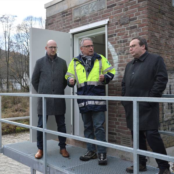 Drei Männer stehen auf einem Metallsteg, der als Zugang für das Pegelhäuschen in Gemünd an der Urft dient.