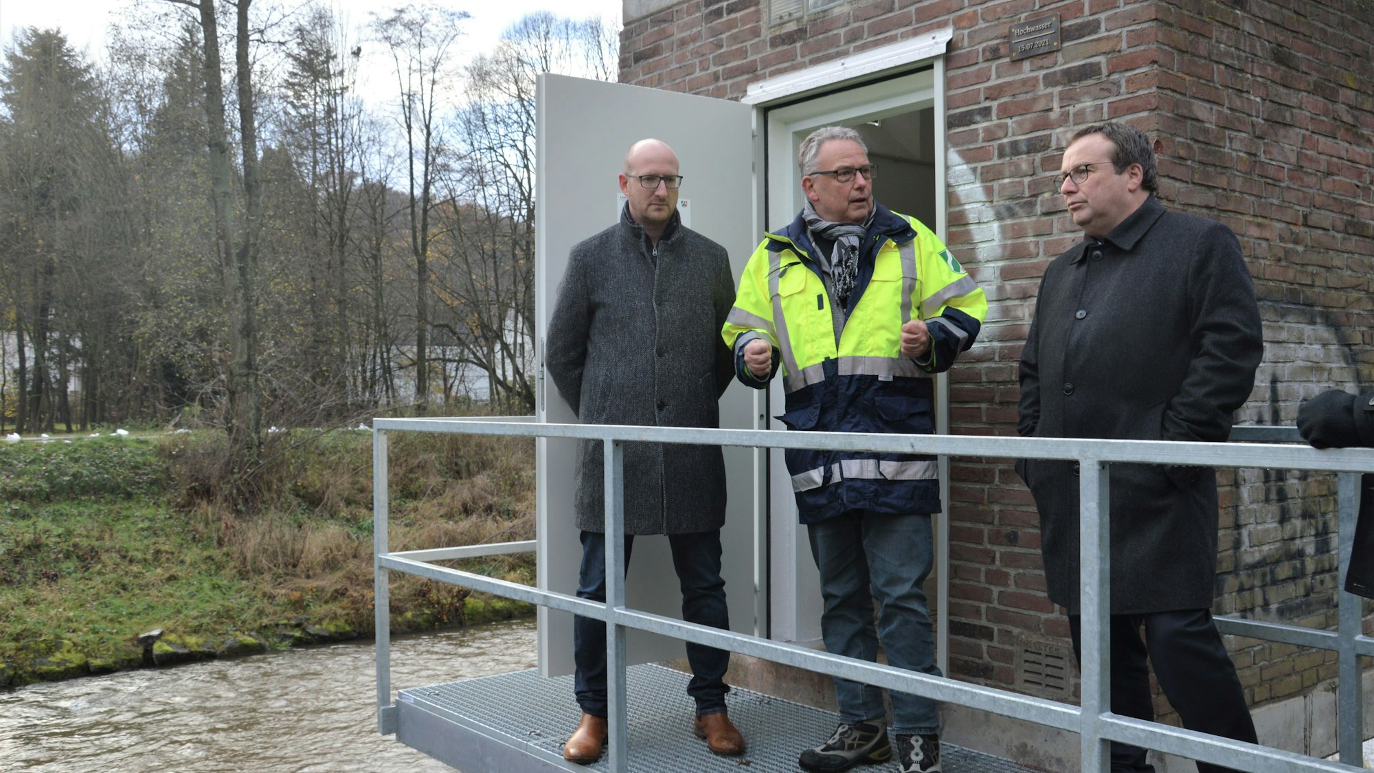 Drei Männer stehen auf einem Metallsteg, der als Zugang für das Pegelhäuschen in Gemünd an der Urft dient.