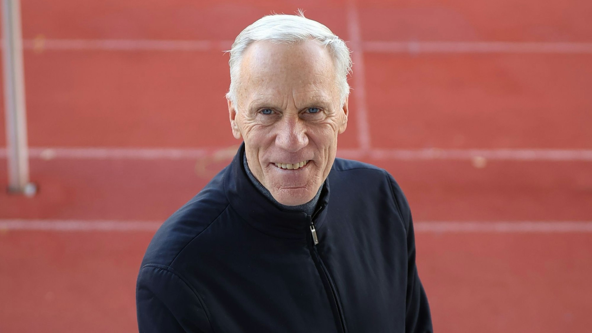 Ingo Froböse steht auf einem Sportplatz und guckt in die Kamera.