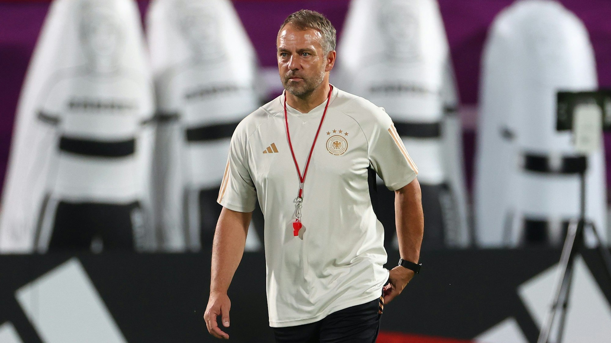 Bundestrainer Hansi Flick im Trikot der deutschen Nationalmannschaft bewegt sich auf einem Trainingsplatz. Im Bildhintergrund sind Freistoß-Dummies zu sehen.