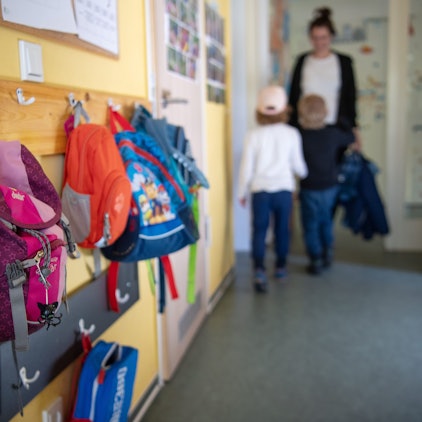 Kinderrucksäcke hängen im Eingangsbereich eines Kindergartens.