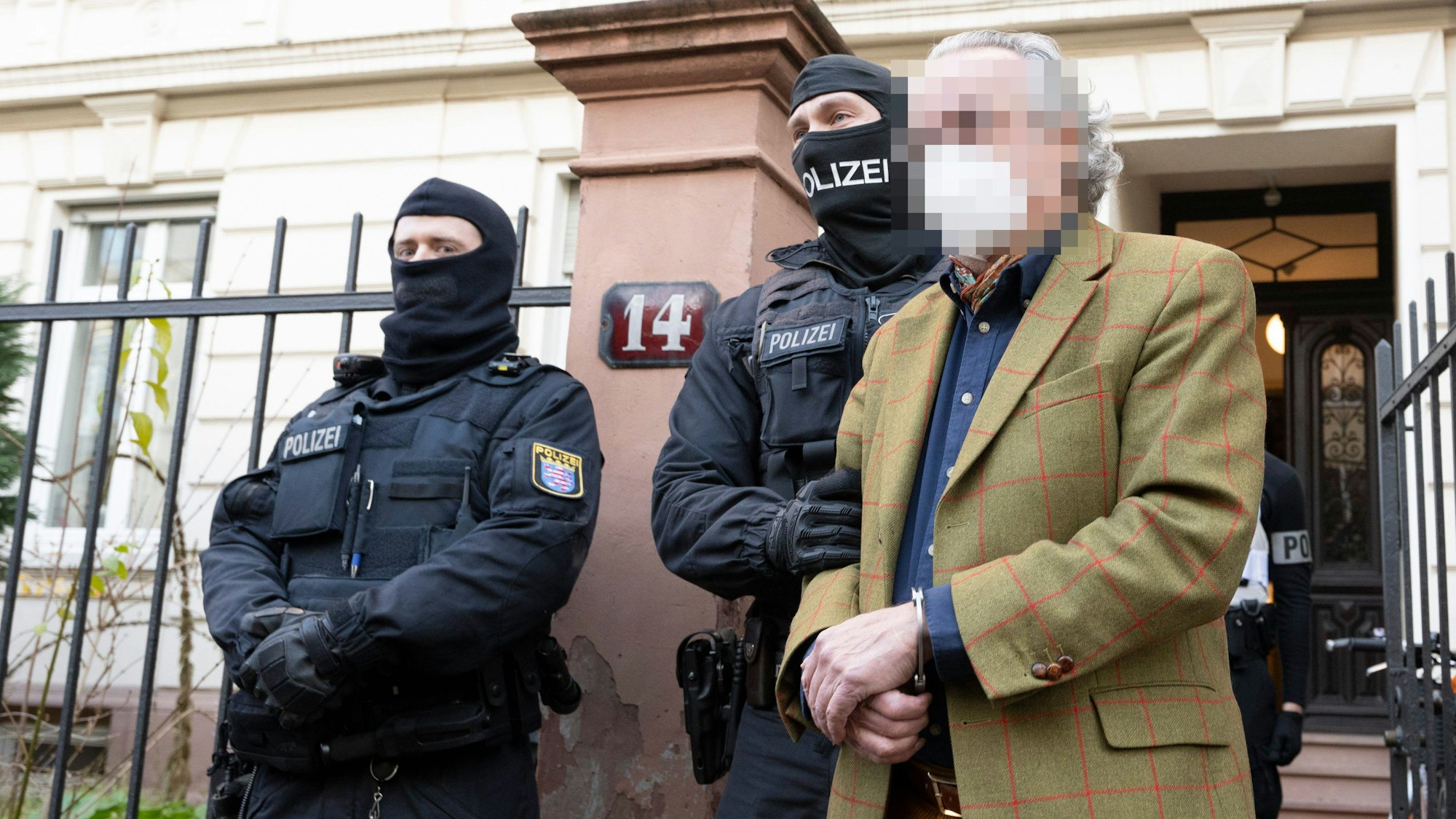 Bei einer Razzia gegen sogenannte „Reichsbürger“ führen vermummte Polizisten, nach der Durchsuchung eines Hauses Heinrich XIII P. R. zu einem Polizeifahrzeug.