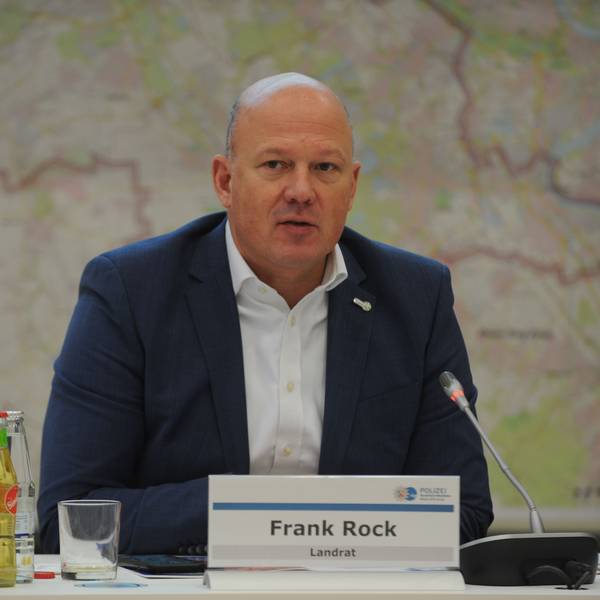 Landrat Frank Rock sitzt während einer Pressekonferenz im Sitzungssaal des Kreishauses und spricht in ein Mikrofon.
