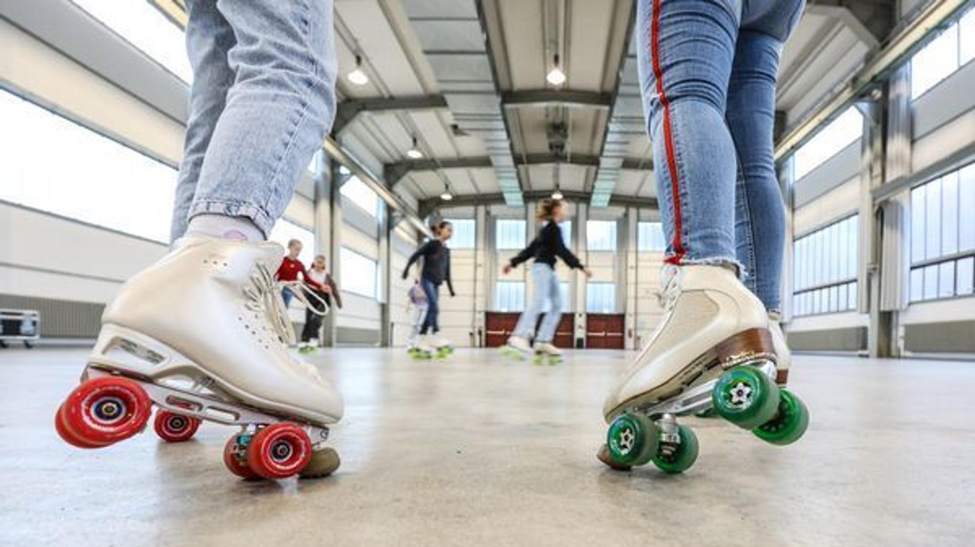 Beine und Füße von zwei Rollschuhläuferinnen in einer Halle
