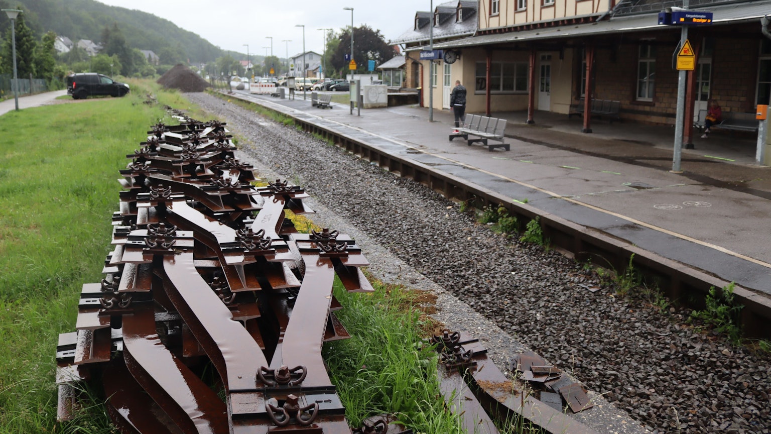 Der Bahnhof Bad Münstereifel an einem regnerischen Tag. Es fehlen infolge der Flut die Gleise, diese liegen aufgestapelt im Vordergrund des Bildes.