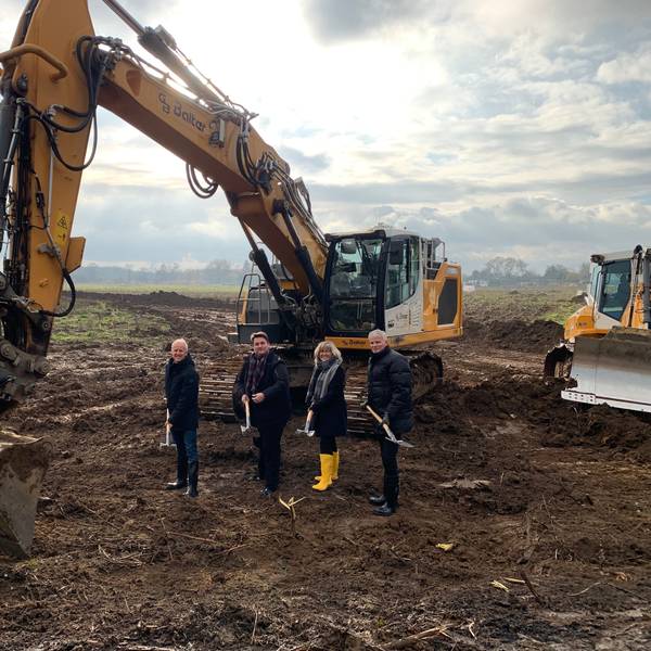 Vor einem Bagger stehen mit Spaten der Technische Beigeordnete der Stadt Troisdorf, Walter Schaaf, Bürgermeister Alexander Biber sowie die Geschäftführung der TroiKomm Andrea Vogt und Michael Roelofs.