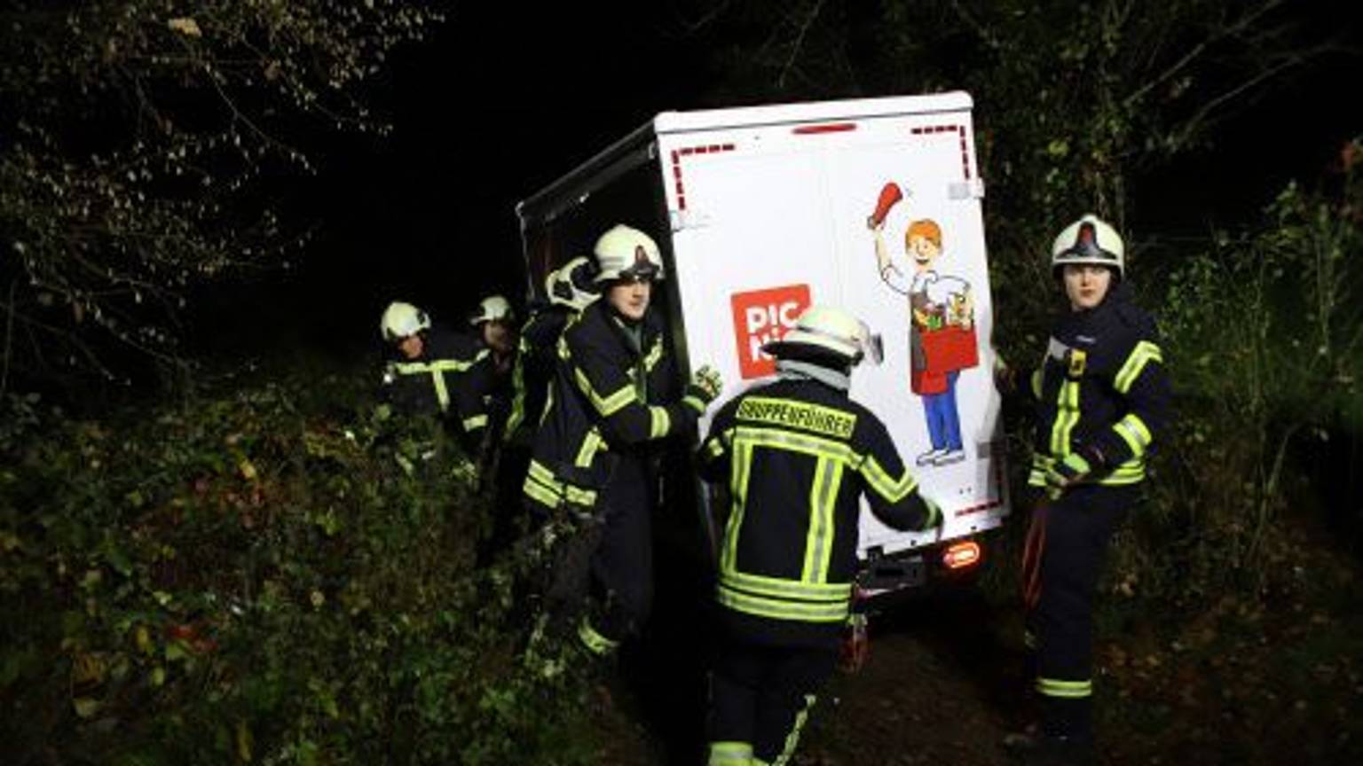Feuerwehrleute stützen einen Van des Lieferdienstes Picnic in einer steilen Böschung.