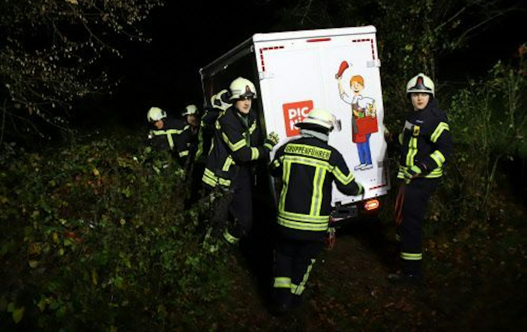 Feuerwehrleute stützen einen Van des Lieferdienstes Picnic in einer steilen Böschung.