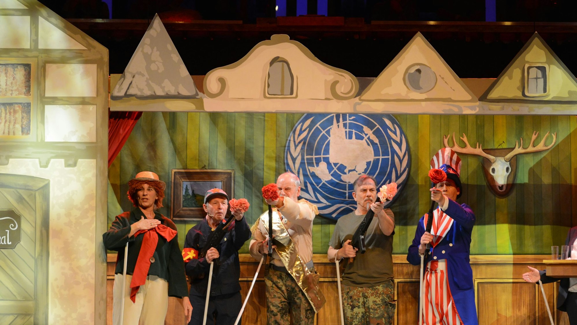 Im Hänneschen Welttheater der Stunksitzung verteilt Speimanes mit Blumen verstopfte Waffen an die Staatsoberhäuter der Weltmächte. Das Bühnenbild zeigt ein Vereinslokal mit eingekölschtem UN-Logo und Hirschgeweih. Die vermeintlichen Stockpuppen werden von Schauspielern dargestellt.