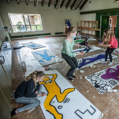 Sechs Kinder arbeiten an Kunstwerken, die auf dem Boden der Evangelischen Kirche in Hilgen ausgelegt sind.