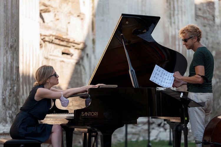 Francesca Tandoi sitzt an einem Flügel, Stefano Senni Duo steht daneben. Sie tragen sommerliche Kleidung und Sonnenbrillen.
