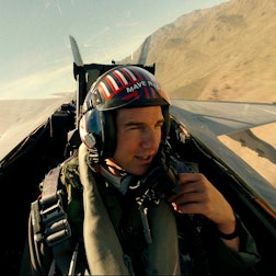 Tom Cruise als Captain Pete „Maverick“ Mitchell in „Top Gun: Maverick“. Er sitz in einem Flieger und spricht in ein Mikrofon an seiner Kleidung.