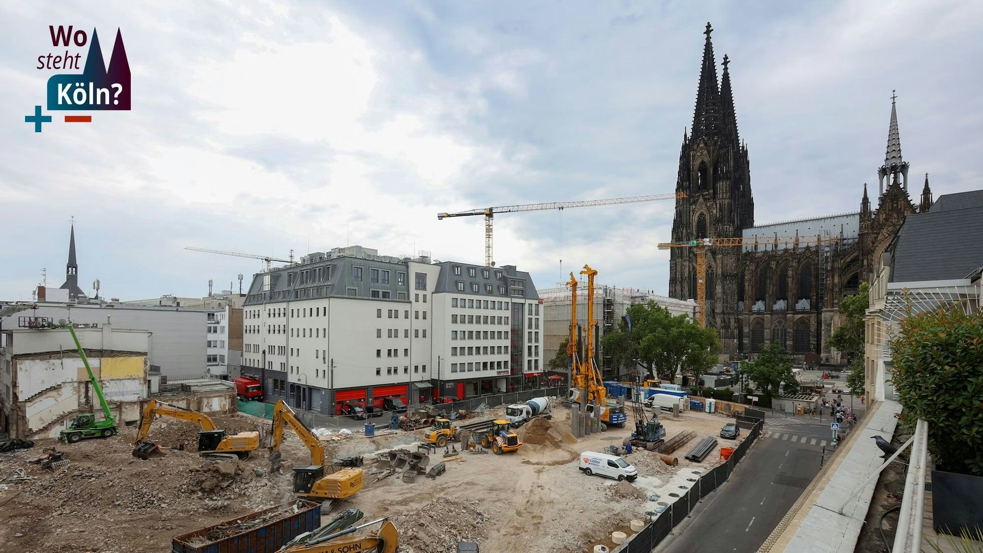 Blick aus südlicher Richtung auf den Kölner Dom, vor dem sich eine riesige Baustelle befindet, auf der das neue Laurenz-Carré entstehen soll. Baustellenfahrzeuge, Kräne und Bagger arbeiten auf der Baustelle.