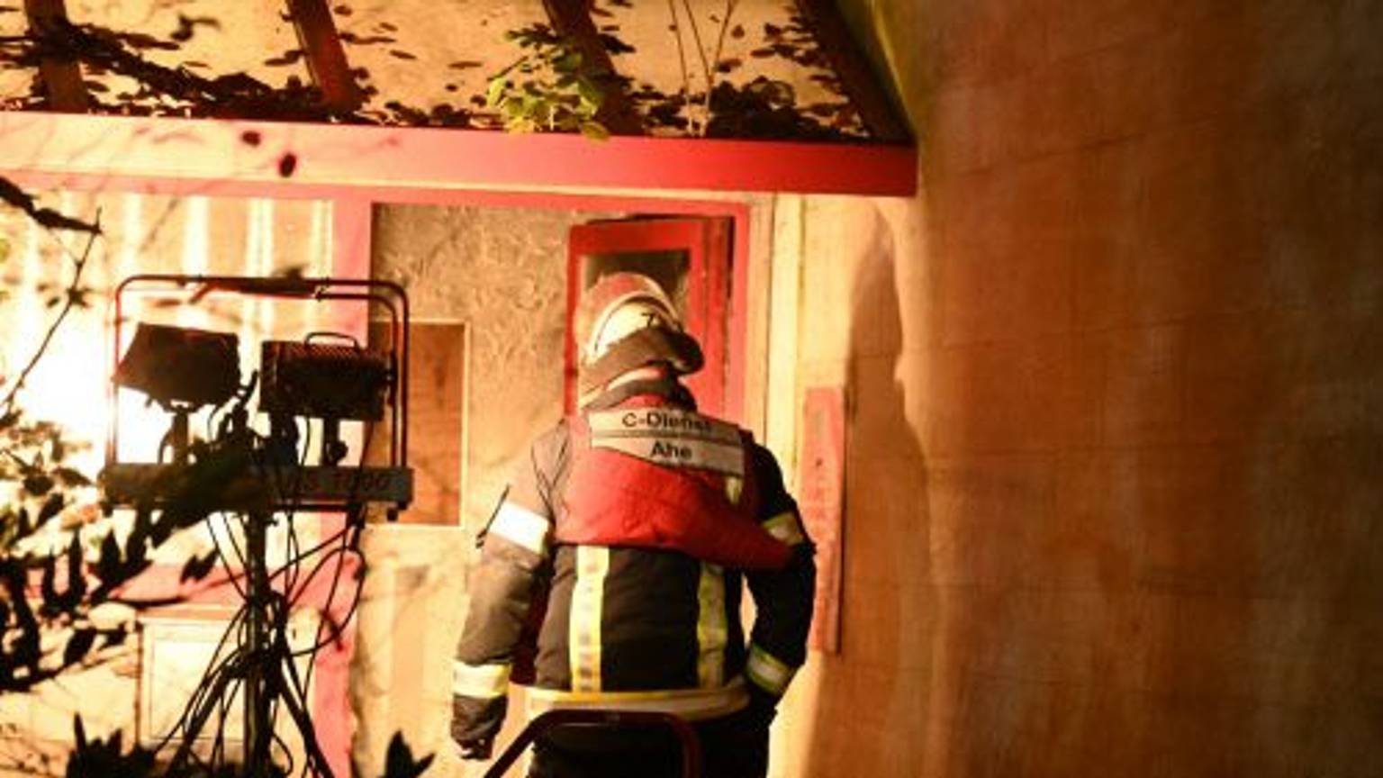Ein Feuerwehrmann betritt das Hochhaus, in dem es gebrannt hat. Starke Scheinwerfer erleichtern ihm die Arbeit