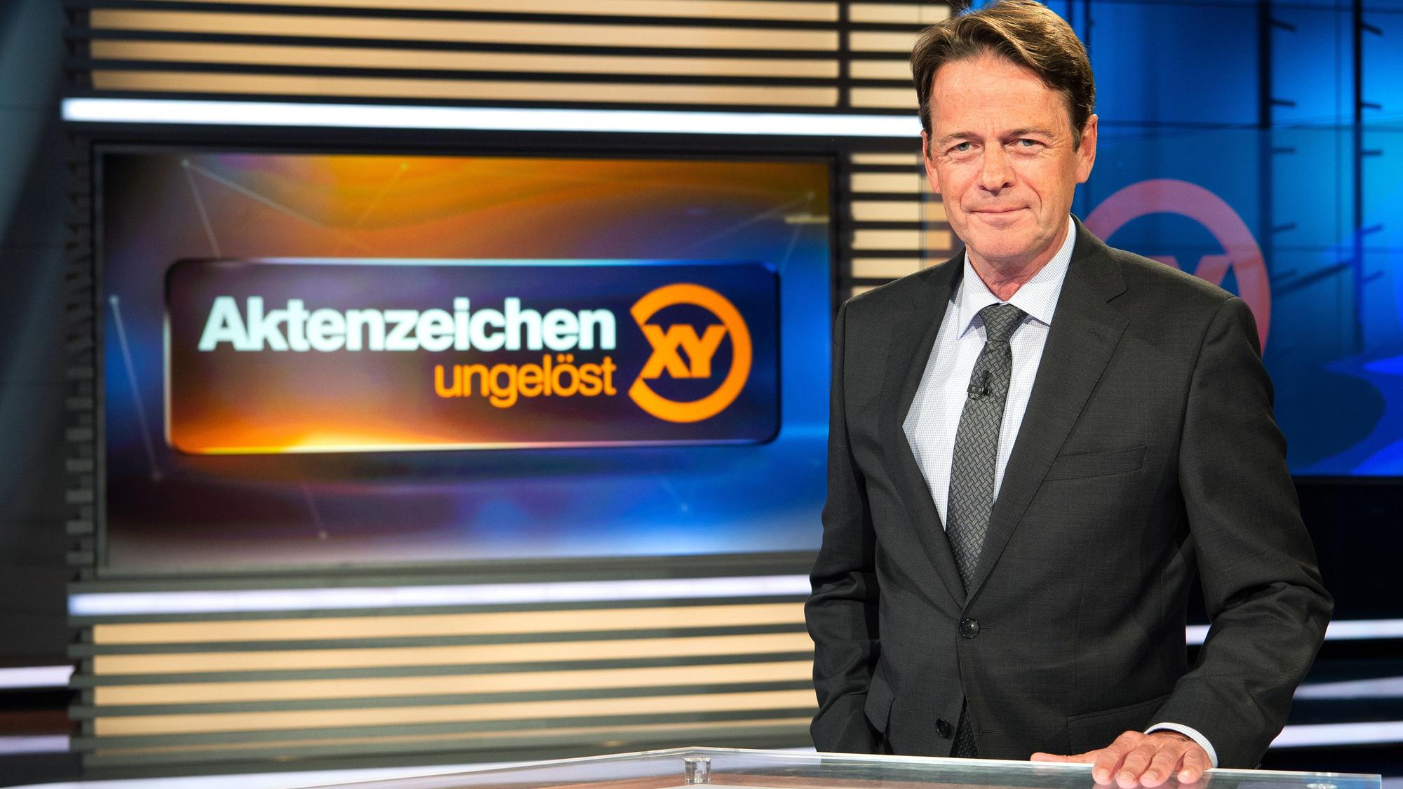Rudi Cerne steht im Studio der Sendung „Aktenzeichen XY ... ungelöst“ und schaut in die Kamera.