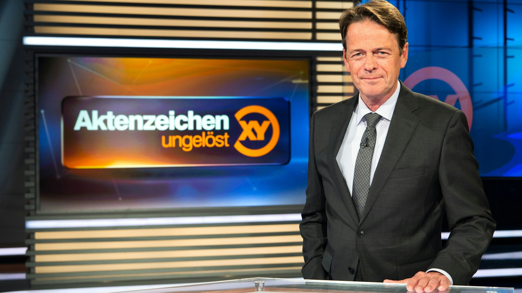 Rudi Cerne steht im Studio der Sendung „Aktenzeichen XY ... ungelöst“ und schaut in die Kamera.