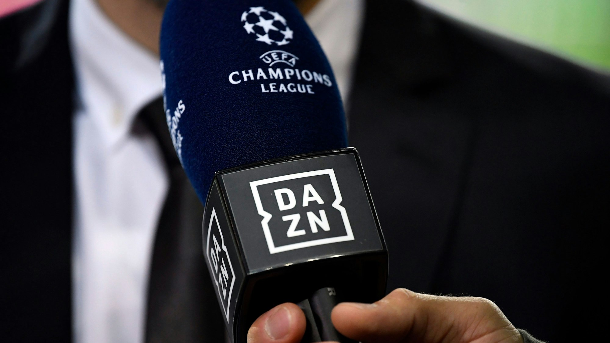 Ein Reporter hält ein Mikrofon des Streamingdienstes DAZN während eines Interviews fest.