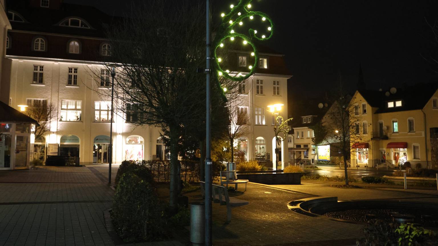 Auf dem dunklen Rathausplatz in Bergneustadt leuchtet eine Lichterkette an einem Laternenmast.