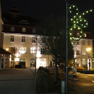 Auf dem dunklen Rathausplatz in Bergneustadt leuchtet eine Lichterkette an einem Laternenmast.