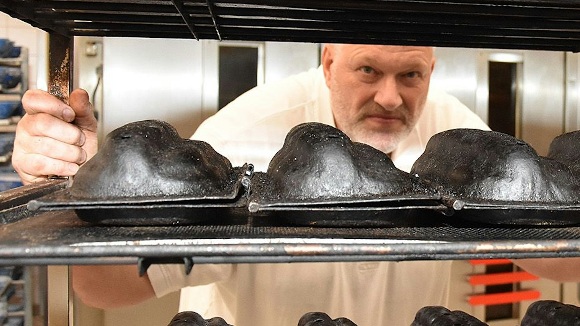 Stefan Felder blickt durch ein Regal mit historischen Stollenbackformen in die Kamera.