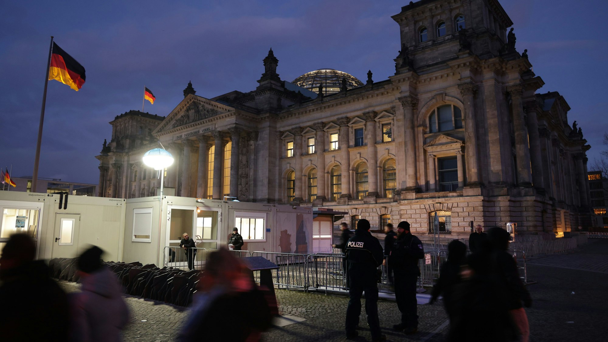 Besucher und Polizisten stehen vor dem Reichstag in Berlin.