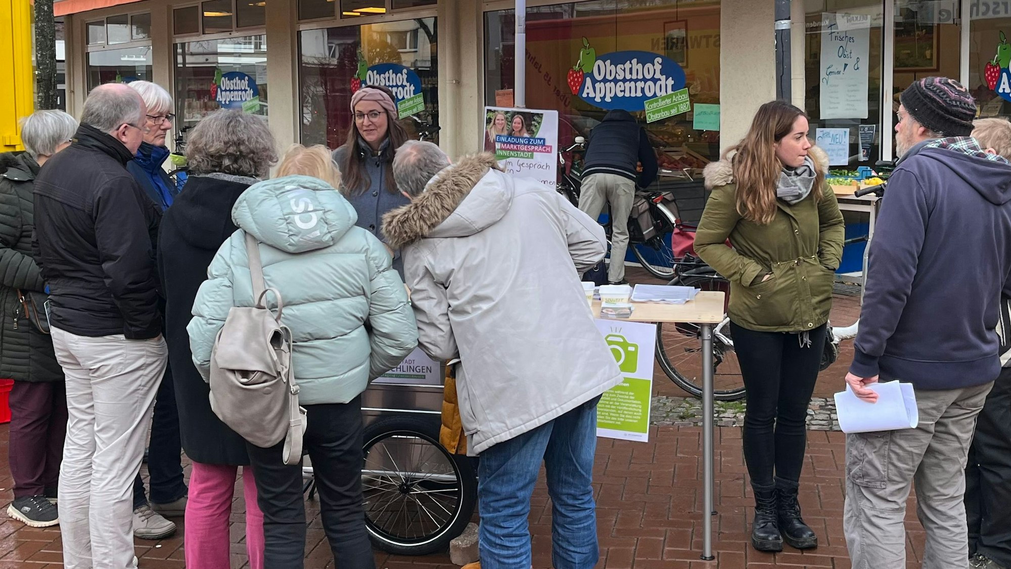 Besucher umringen den Infostand der Stadtnetzwerkerinnen auf dem Wochenmarkt, Linda Nebel vom Planungsamt beantwortet Bürgerfragen.