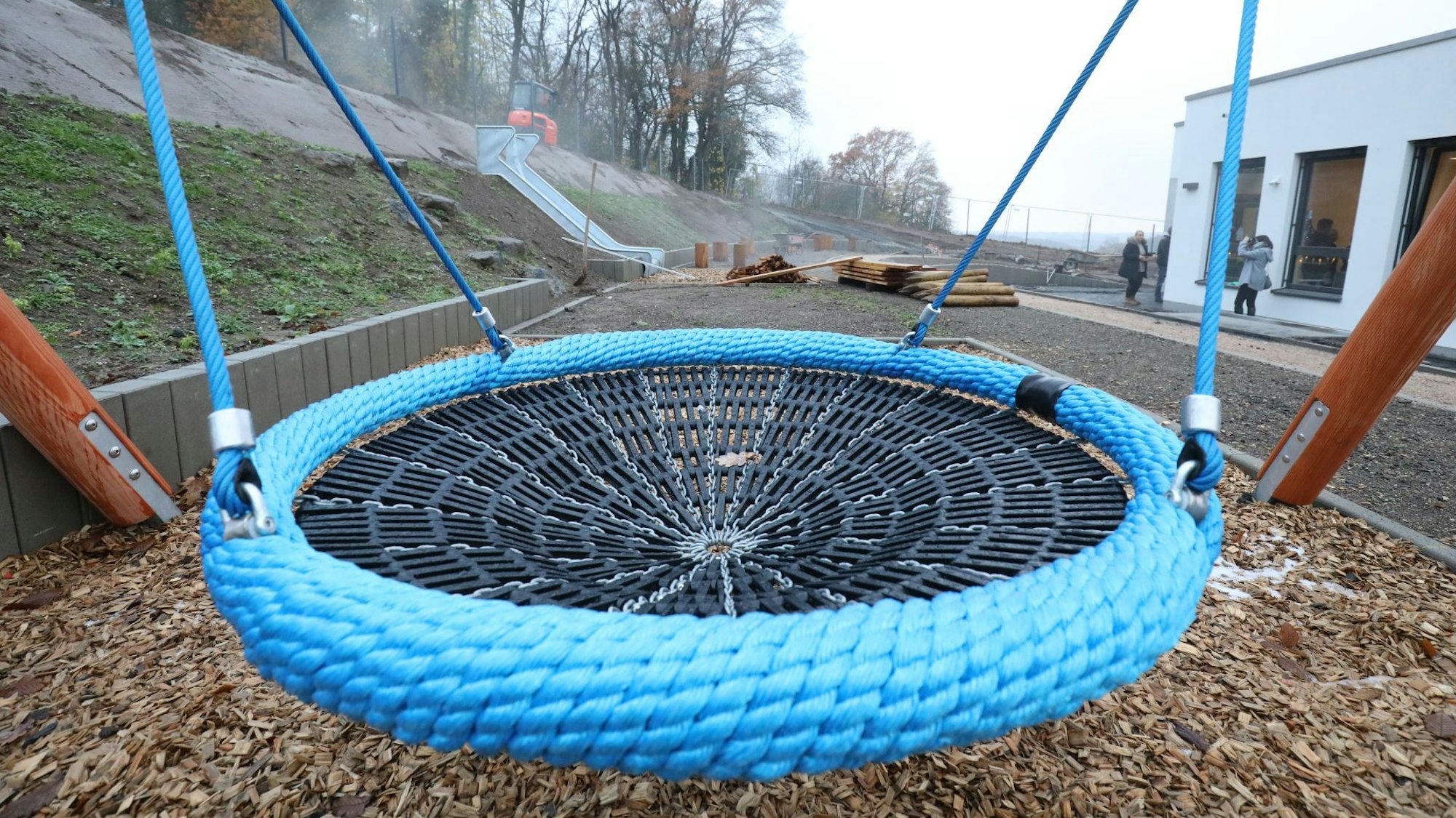 Eine große runde Schaukel steht neben dem Gebäude einer Kita.