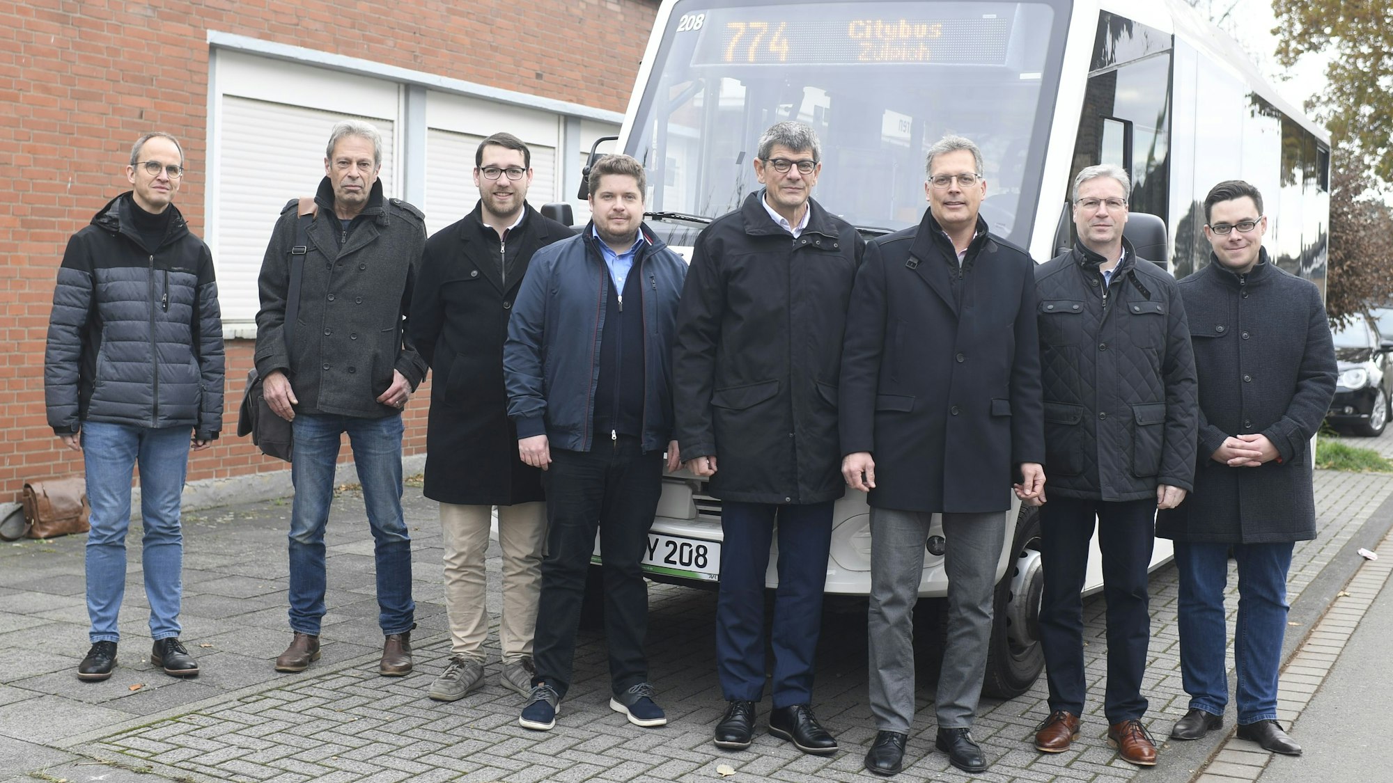 Eine Delegation aus Kreis, Stadt und regionalen Verkehrsbetrieben steht bei der Pressekonferenz für das neue ÖPNV-Konzept Zülpich vor dem Seepark-Kleinbus 774.