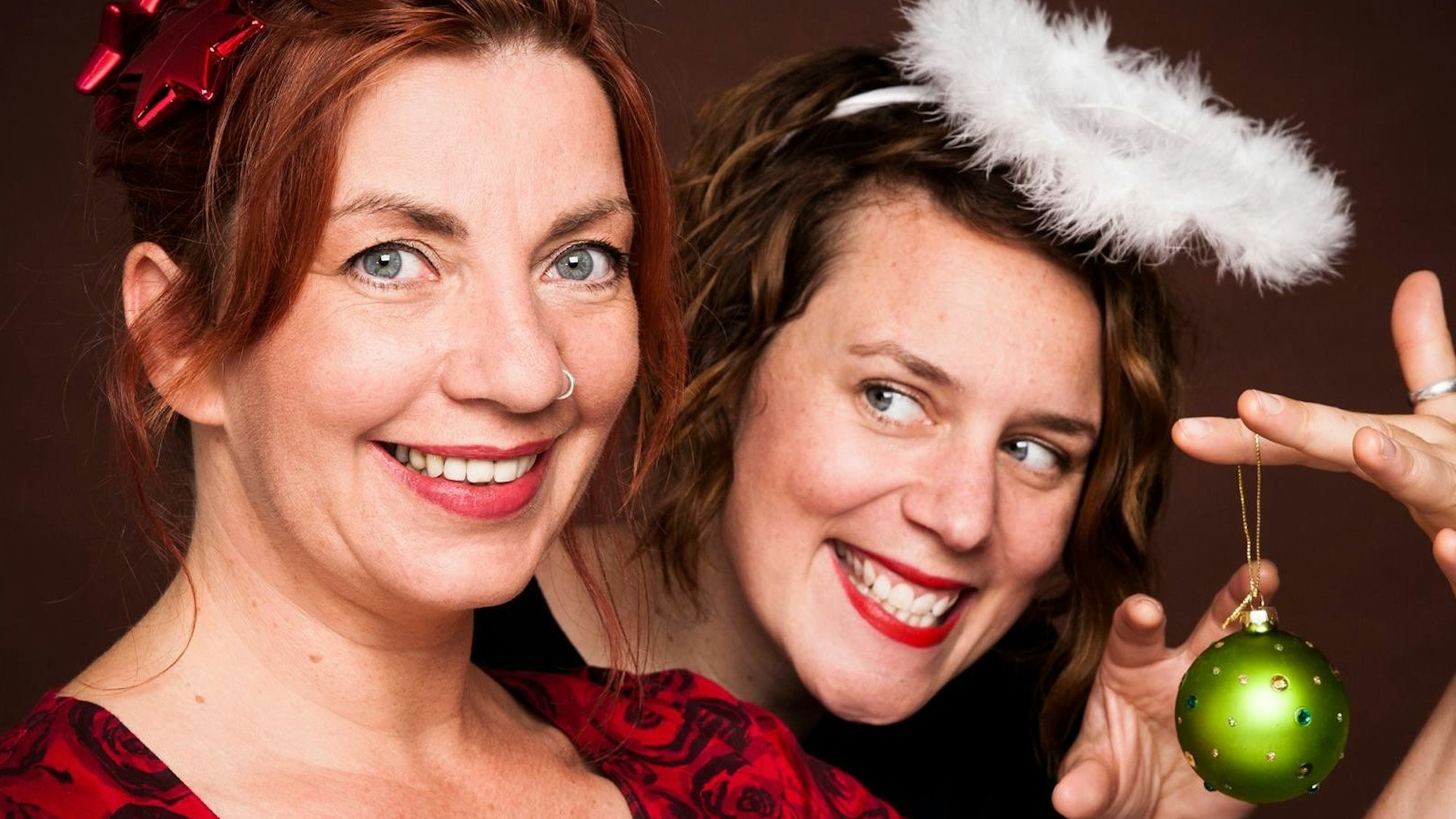 Anika Auweiler (r.) trägt einen Kostüm-Heiligenschein und Dagmar Schönleber eine rote Geschenkschleife im Haar.