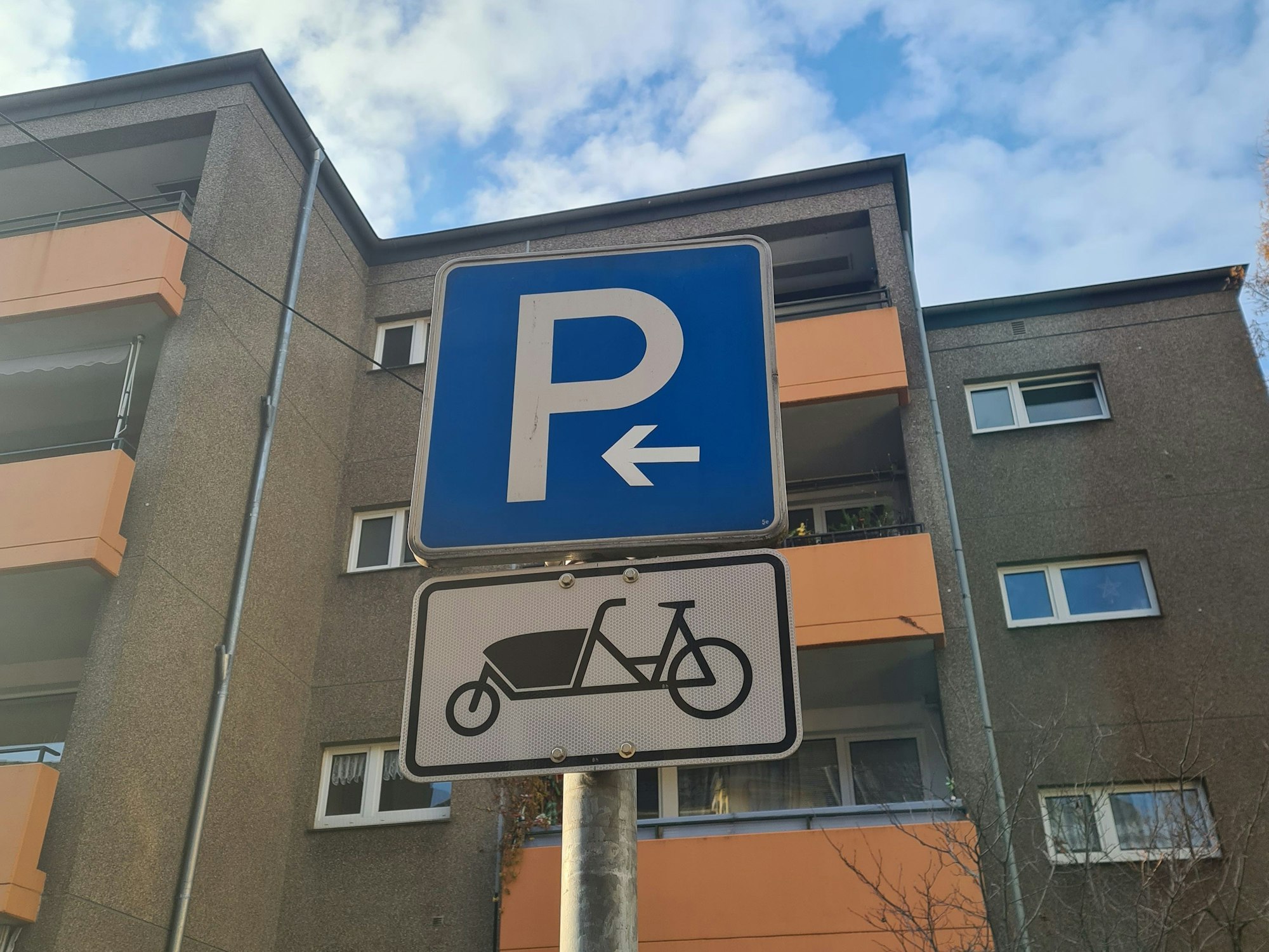Auf einem neuen Schild ist ein Lastenrad zu sehen. Es weist zusammen mit einem Parkplatz-Schild auf die neuen KVB-Lastenrad-Stationen hin.