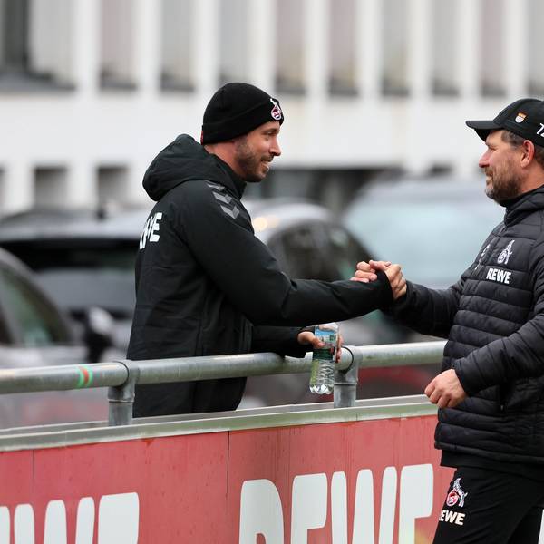 Kölns verletzter Offensivspieler Mark Uth (l.), der eine schwarze Mütze trägt, begrüßt FC-Coach Steffen Baumgart am Rande der Trainingseinheit.