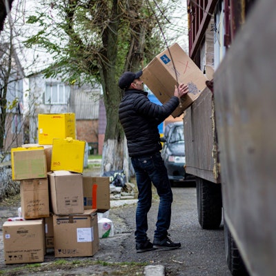 Ein Mann hebt Pakete von einem Fahrzeug.
