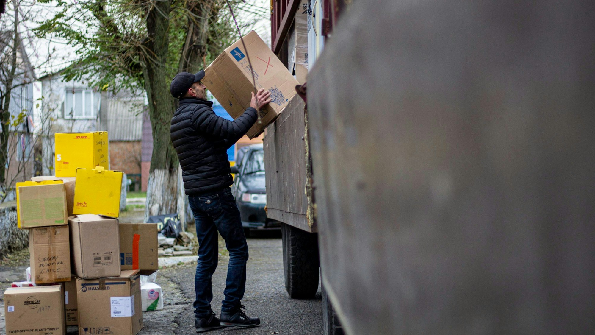 Ein Mann hebt Pakete von einem Fahrzeug.