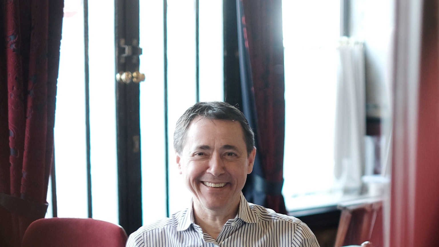 Portrait eines lächelnden Mannes mit gesteiftem Hemd.