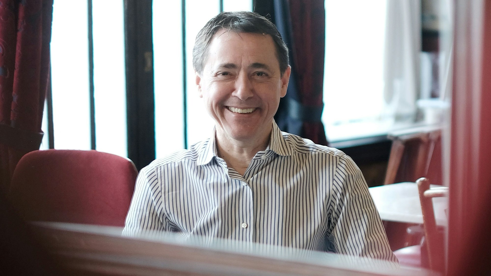 Portrait eines lächelnden Mannes mit gesteiftem Hemd.