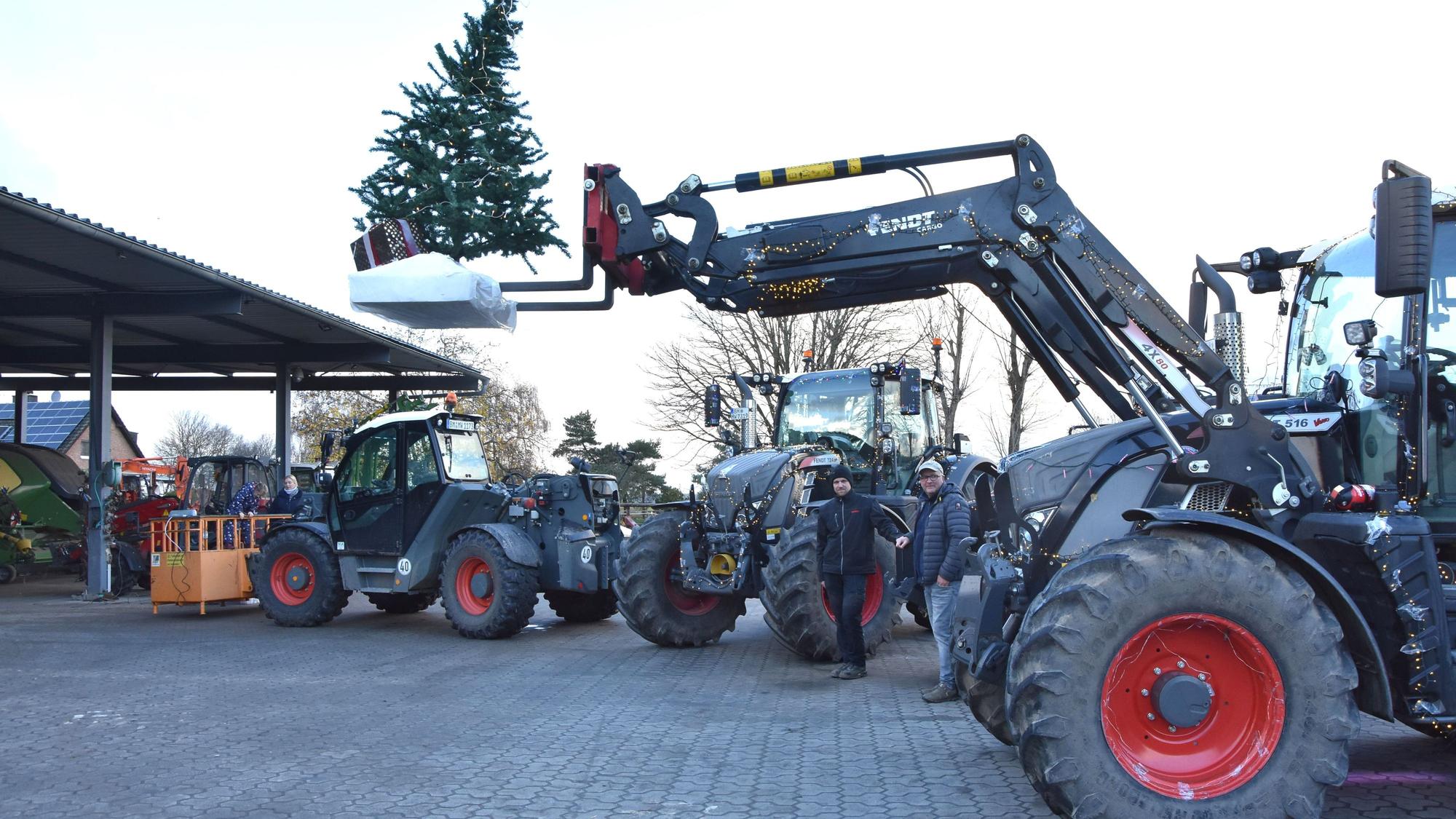 Mehrere Traktoren stehen auf einem Hof, zwei Männer in der Mitte. Ein Traktor hebt einen Tannenbaum.