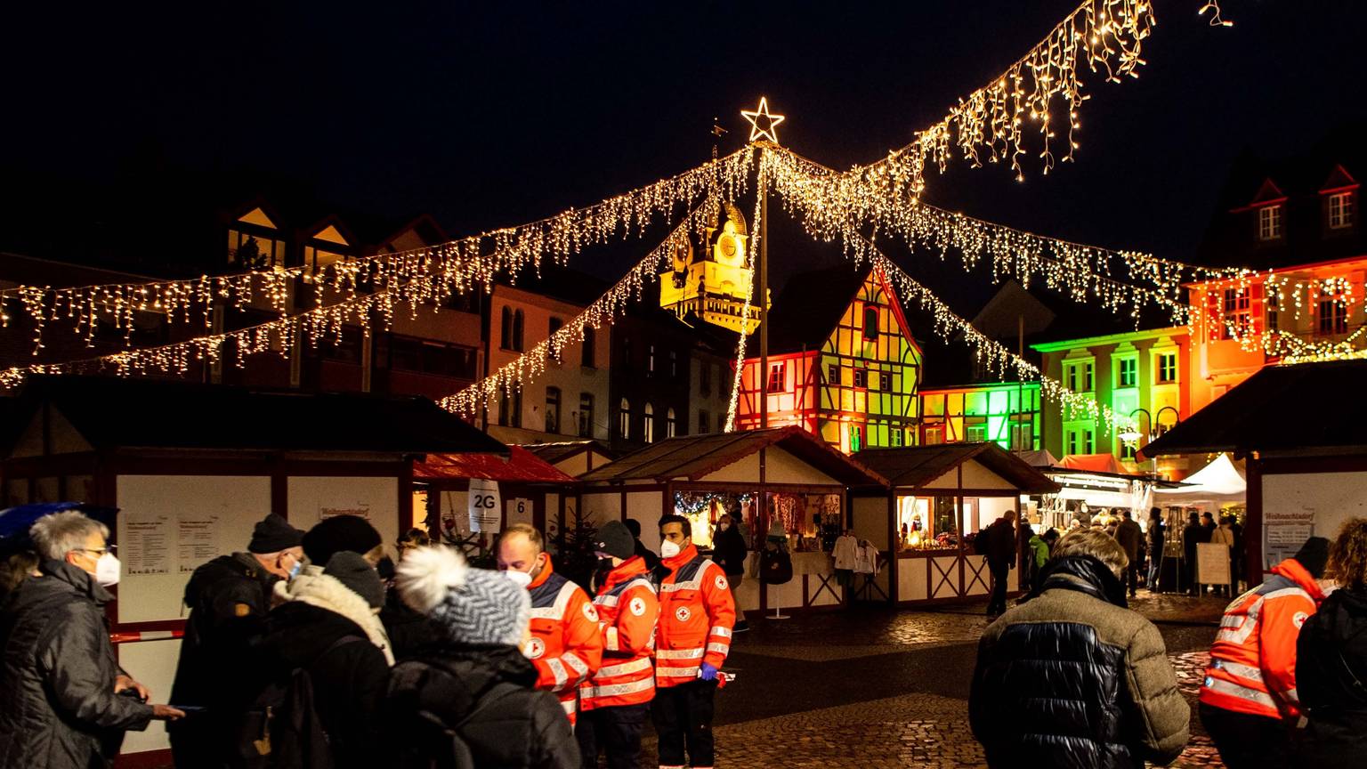 Über weihnachtlichen Buden glänzt eine festliche Sternenbeleuchtung.
