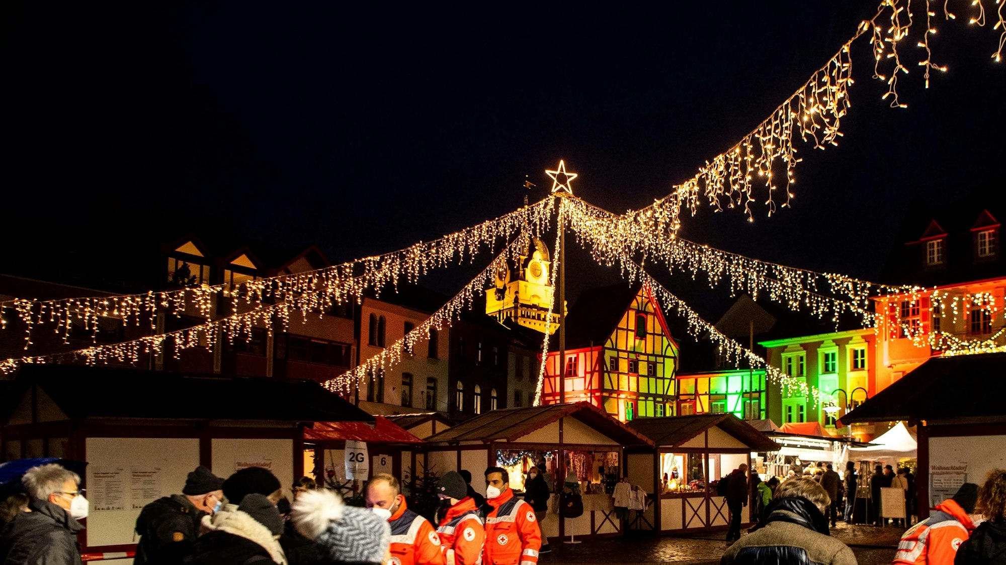 Über weihnachtlichen Buden glänzt eine festliche Sternenbeleuchtung.