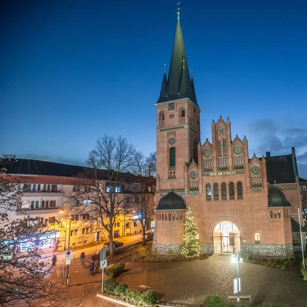 Die evangelische Christuskirche in Wiesdorf. Vor der Kirche steht zur Weihnachtszeit ein geschmücktem Tannenbaum.