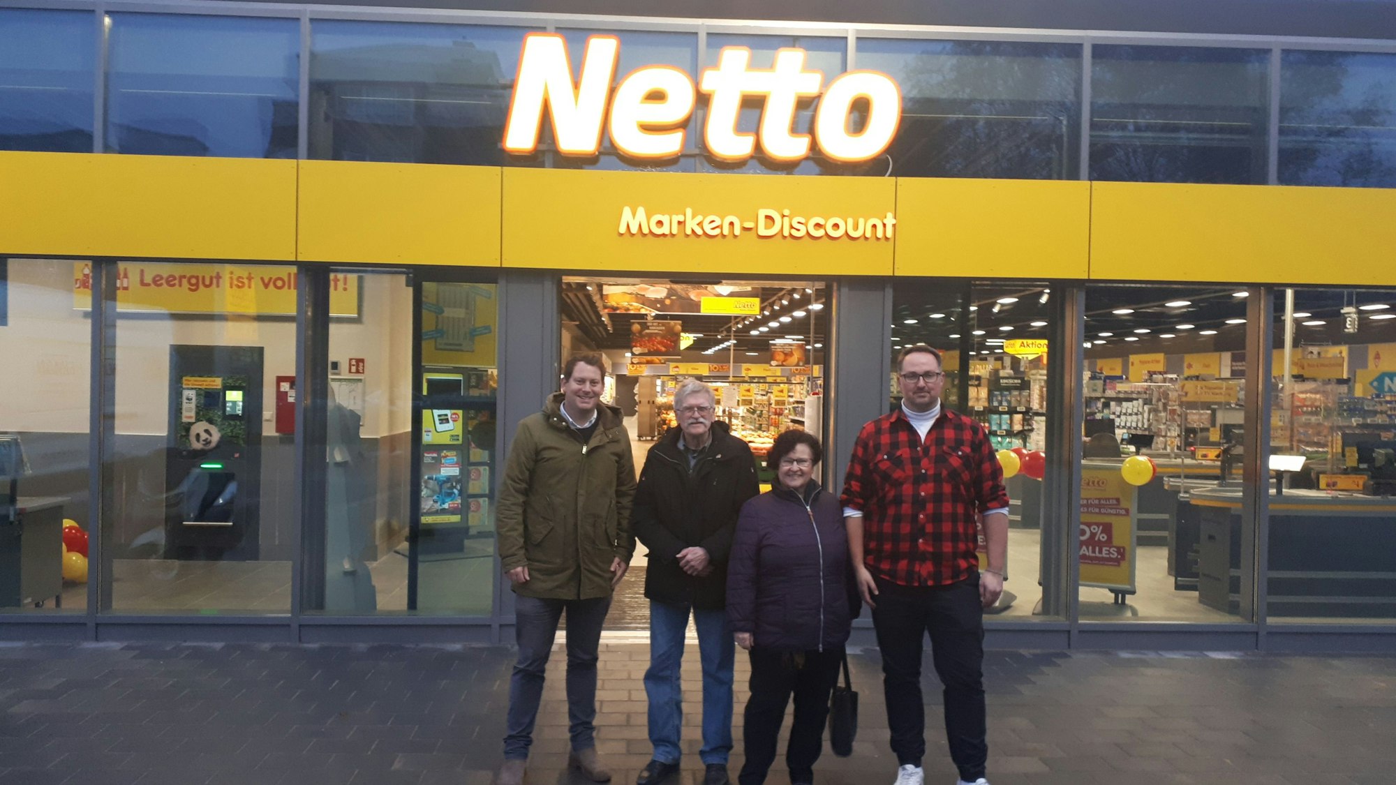 Drei Männer und eine Frau stehen vor dem Eingang des Netto-Supermarktes in Bilderstöckchen