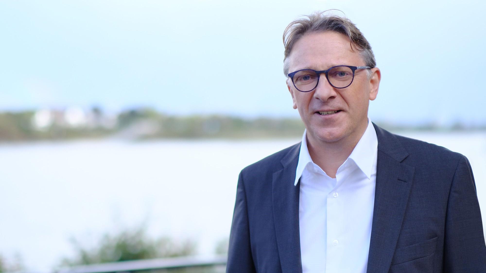 Elmar Gillet in einem weißen Hemd und dunkelblauen Jackett.