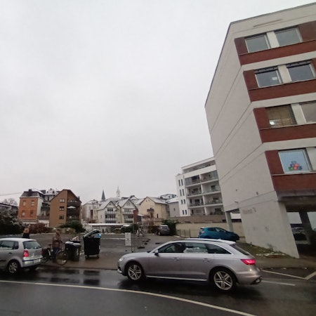 Zwei Autos fahren auf der Straße an dem Baugrundstück in der Sieburger Innenstadt an der Wilhelmstraße vorbei. Das Grundstück liegt zwischen Wohn- und Bürogebäuden und dem Gymnasium Alleestraße.