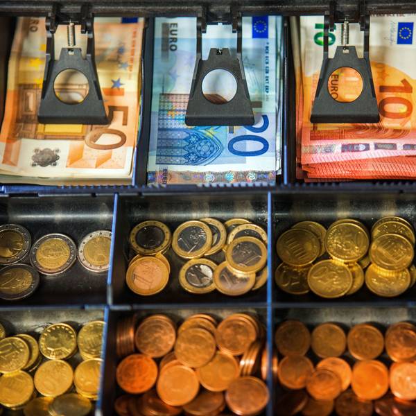 Das Geldfach einer Ladenkasse mit Münzen und Scheinen darin.