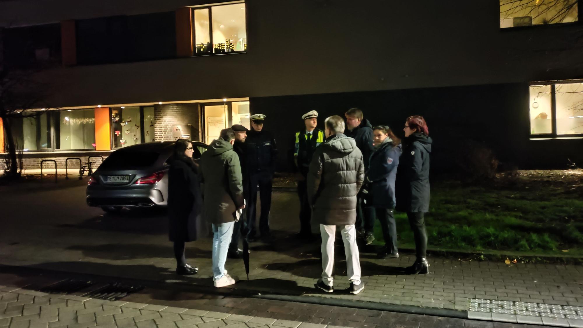 Eine Menschengruppe, darin uniformierte Polizisten, steht vor der Kita an der Hitdorfer Ringstraße, im Gespräch.