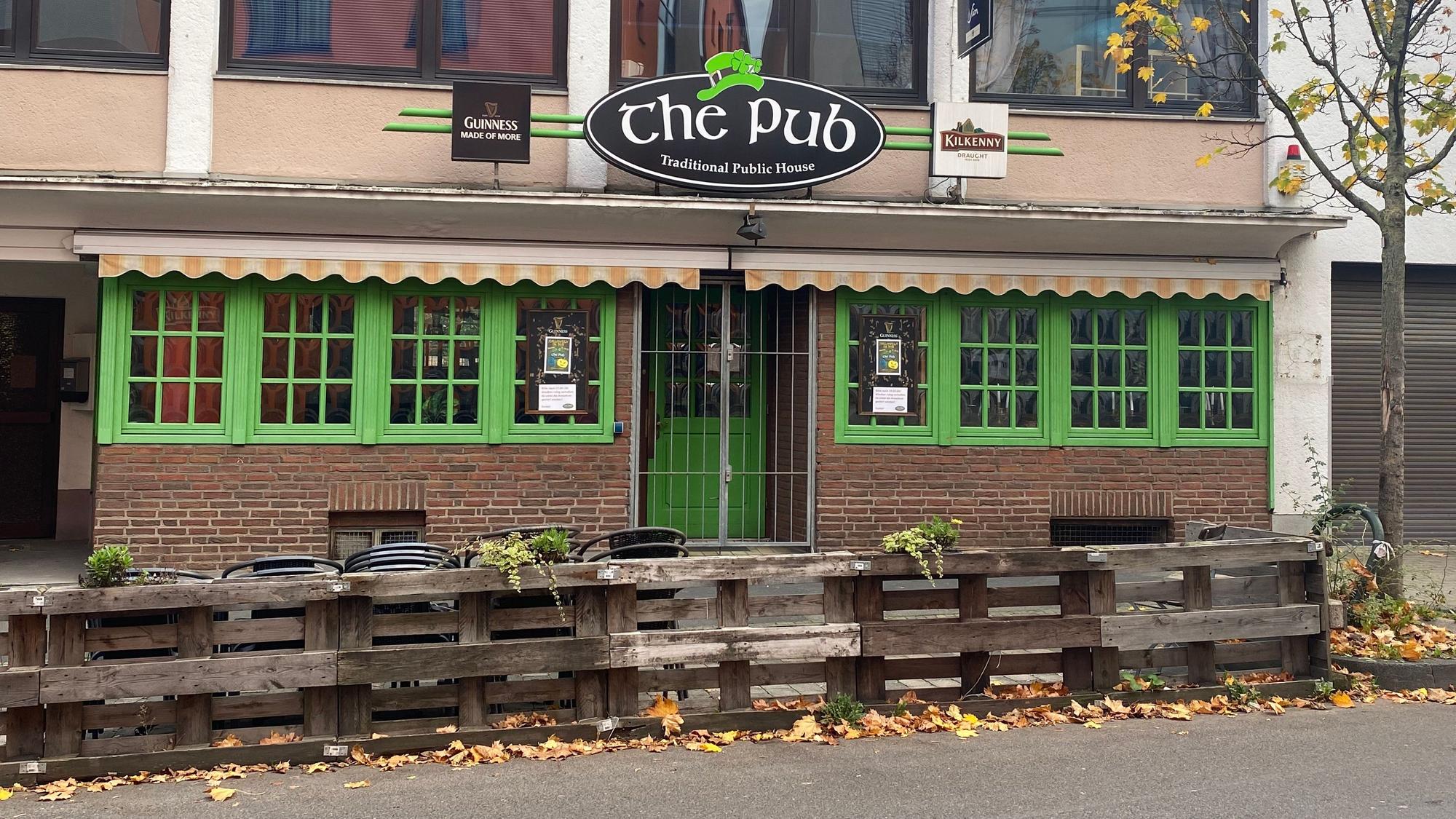 Blick auf die Fassade des The Pub. Die Fensterläden und die Eingangstür sind knallgrün gestrichen.